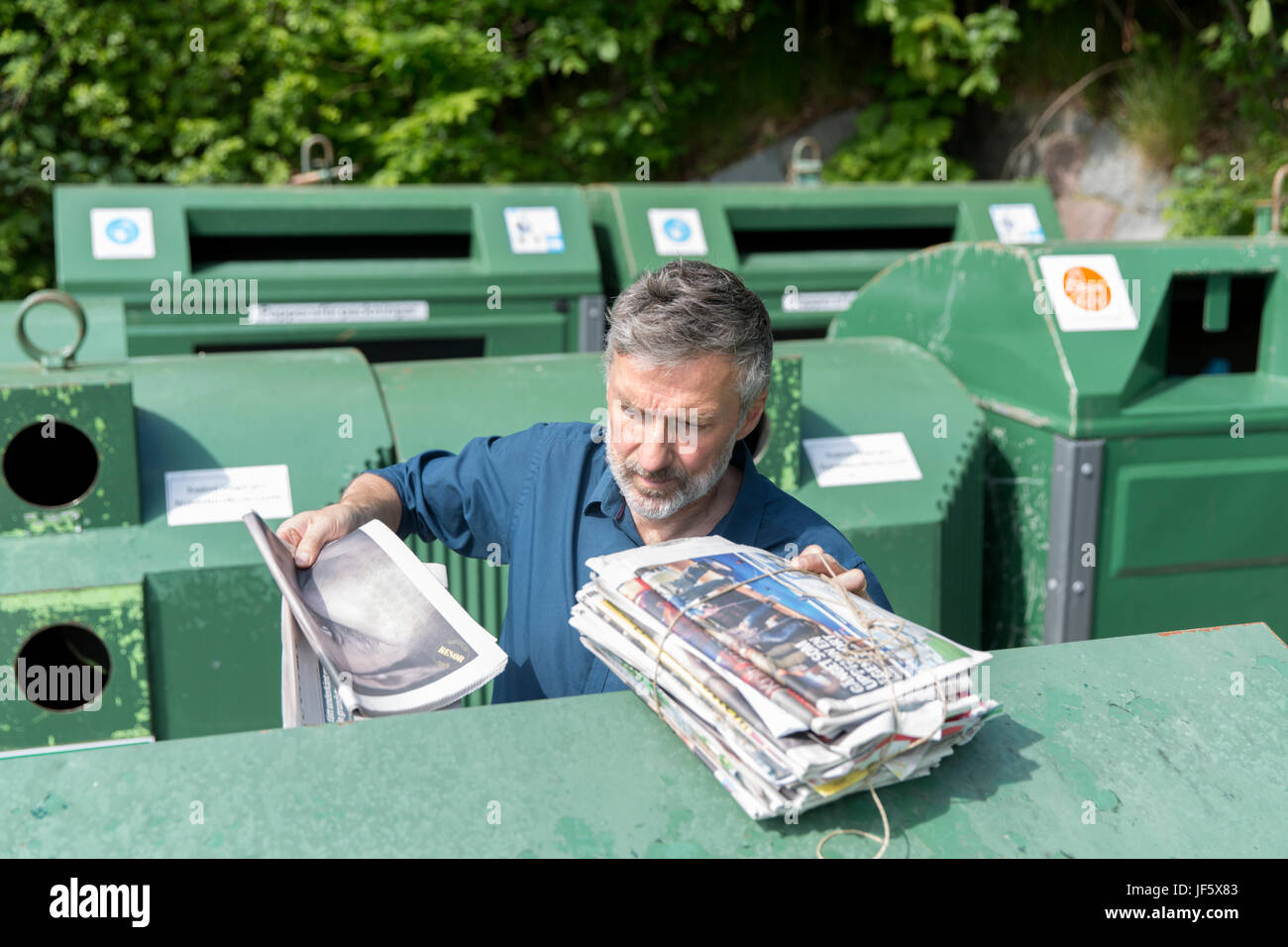 Man throwing paper into recycling bin Stock Photo