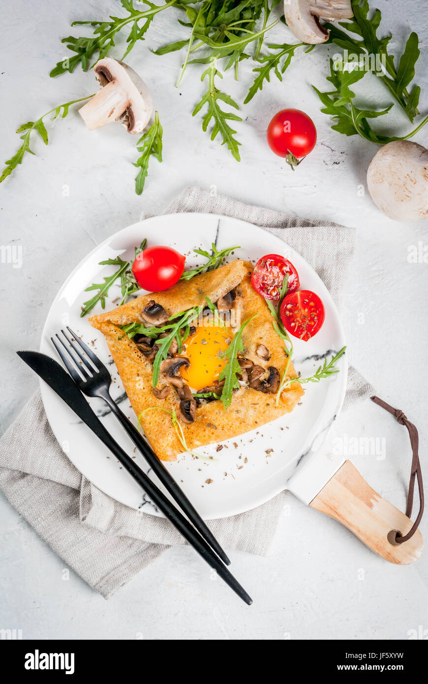 French cuisine. Breakfast, lunch, snacks. Vegan food. Traditional dish galette sarrasin. Crepes with eggs, cheese, fried mushrooms, arugula leaves and Stock Photo