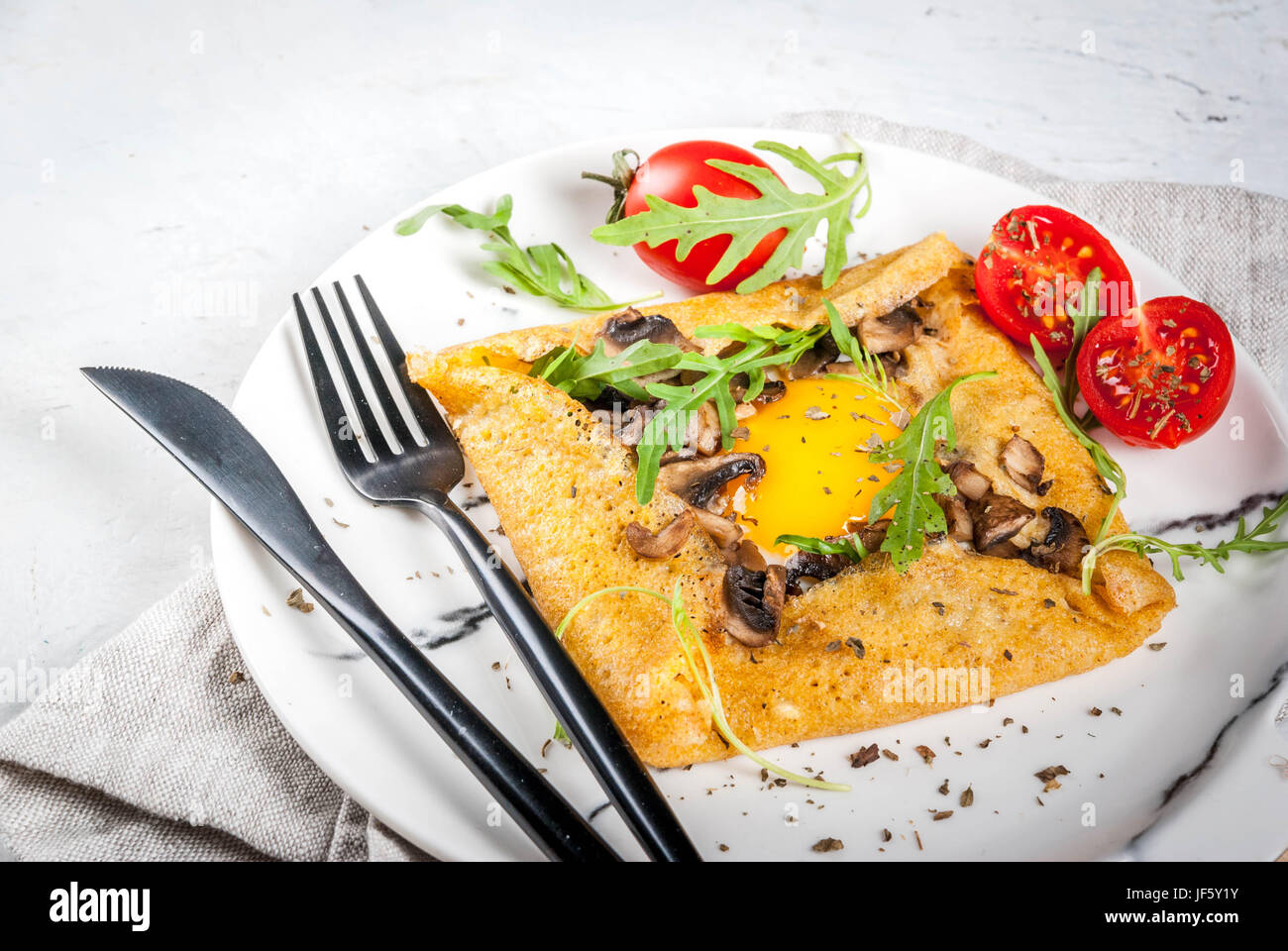 French cuisine. Breakfast, lunch, snacks. Vegan food. Traditional dish galette sarrasin. Crepes with eggs, cheese, fried mushrooms, arugula leaves and Stock Photo