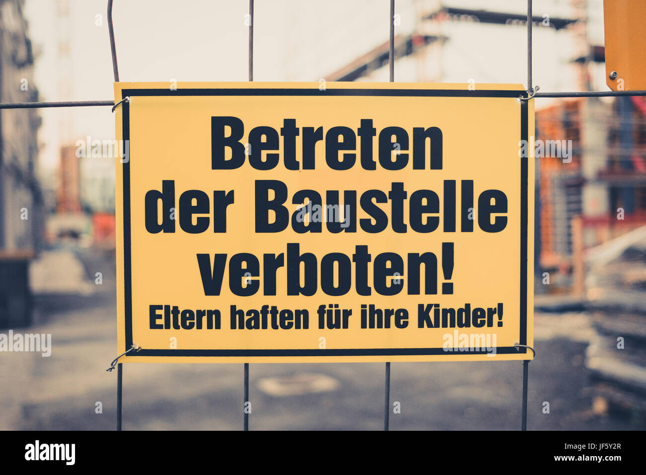 Yellow sign in german: Betreten der Baustelle verboten! Eltern haften für ihre Kinder! translation: entering the building site prohibited. Parents are Stock Photo