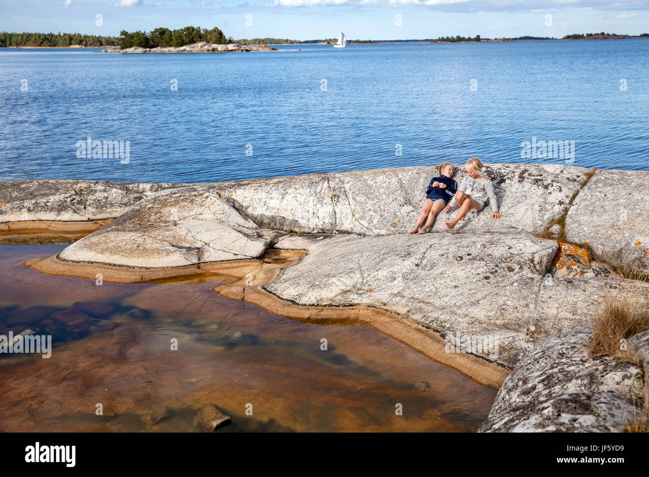 Two girls sitting on rock Stock Photo - Alamy
