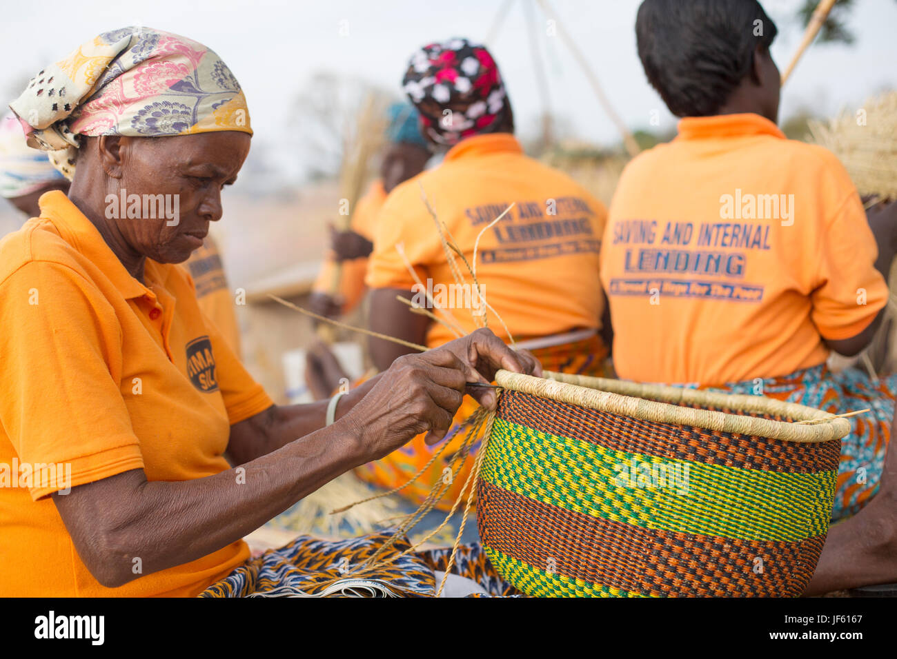 Women from a weaver’s cooperative weave traditional straw baskets together in Upper East Region, Ghana. Stock Photo