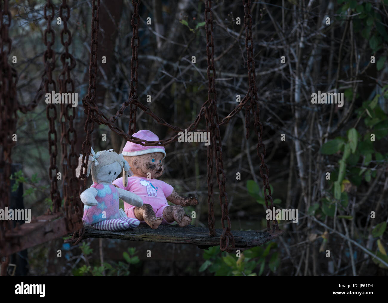 Abandoned childs doll and soft toy on swing Stock Photo