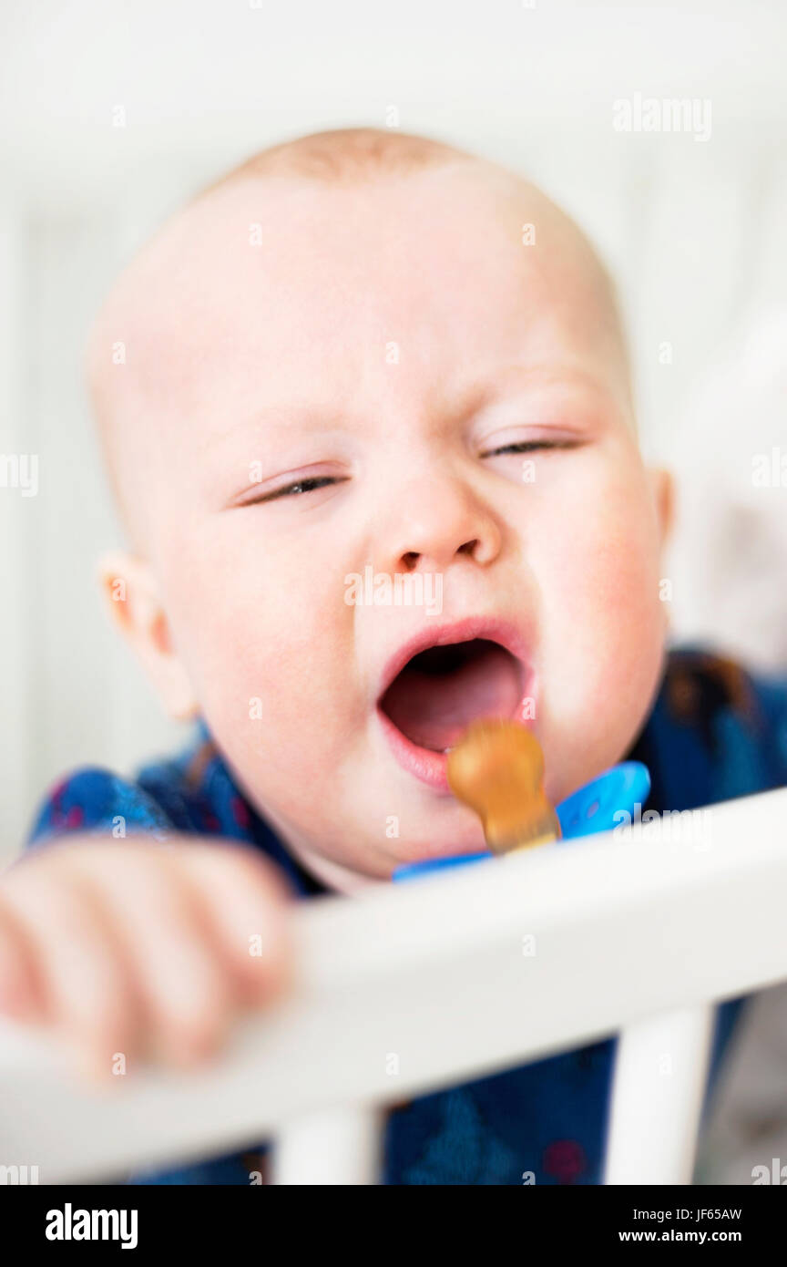 Baby boy crying in cot Stock Photo