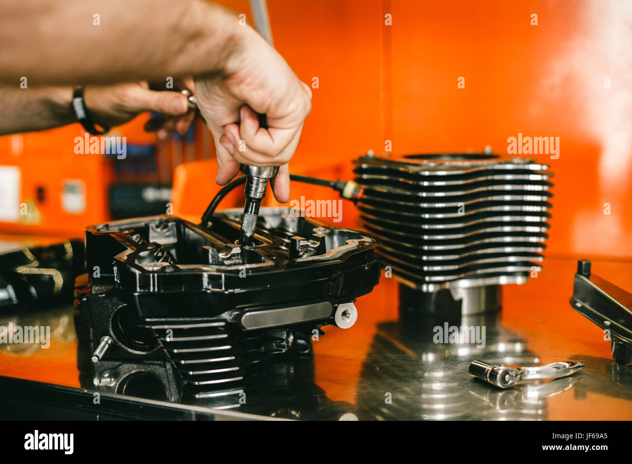 Cropped image of automobile mechanic repairing motorcycle in automobile store. Biker repairing his custom motorcycle Stock Photo