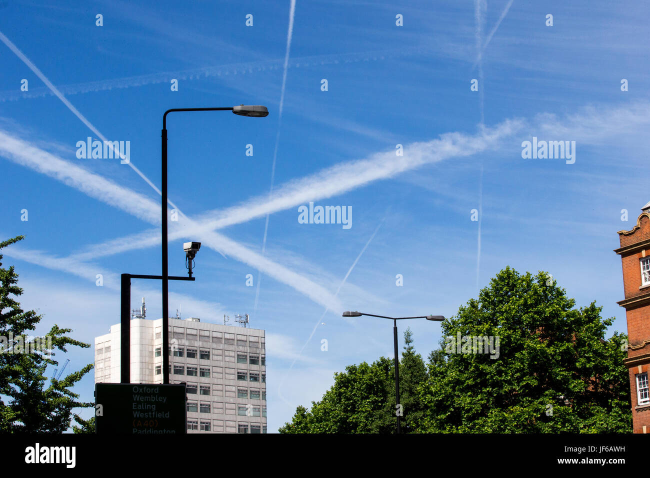 Airplane contrails over the sky in London.These show the trails left by aircraft that turn into clouds and pollute the environment Stock Photo