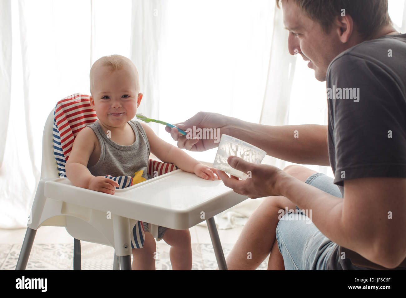 Father feeding cute baby at home Stock Photo