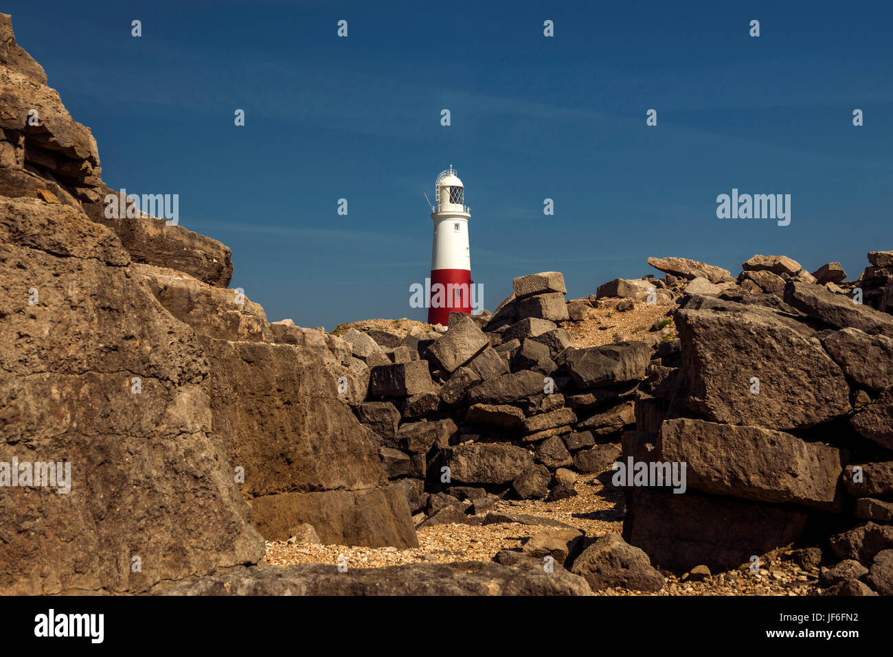 Portland Bill Lighthouse on a beautiful summers day, depicting the Quarries rock and boulder formation in the foreground with a clear blue sky. Stock Photo