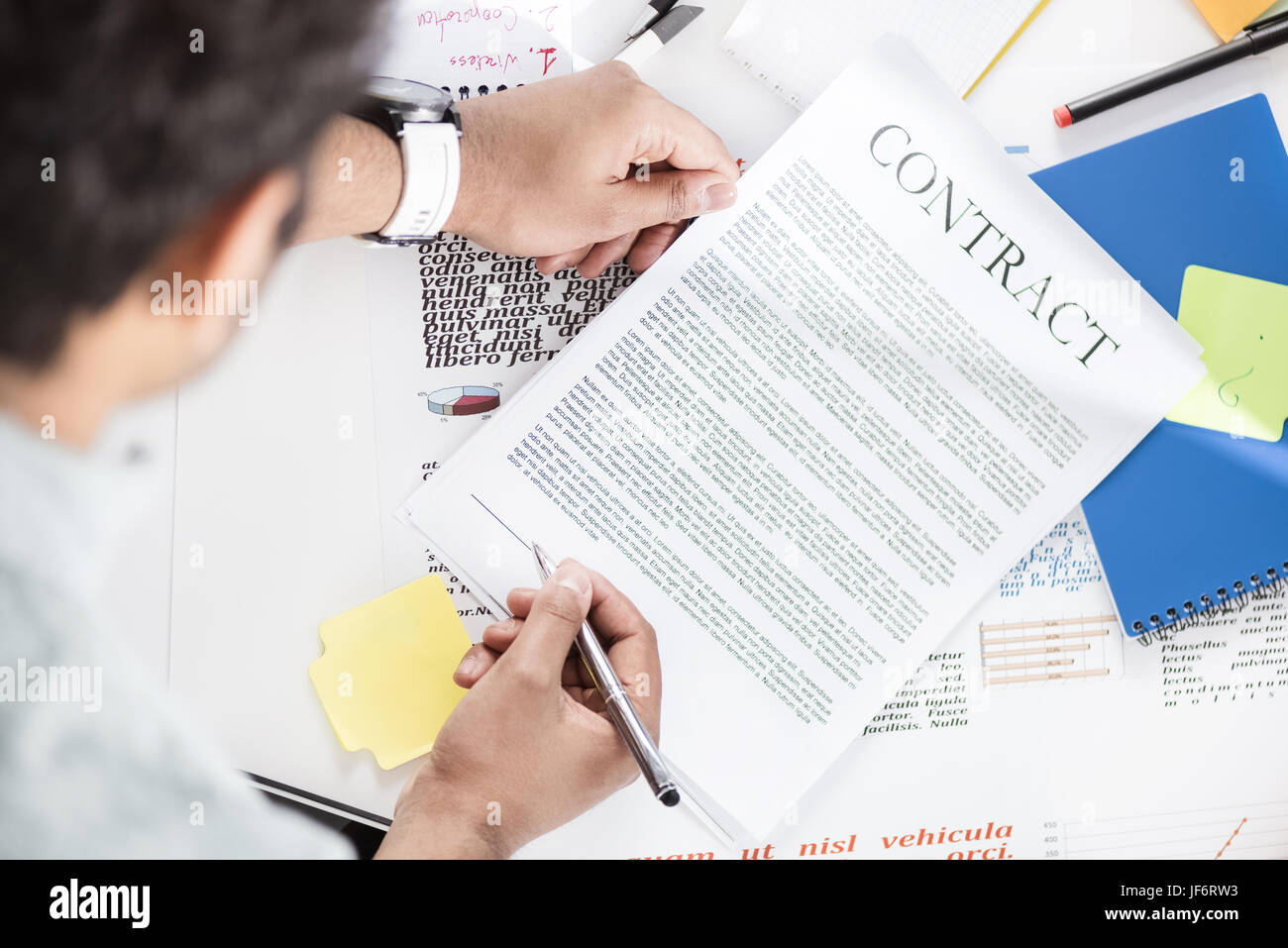 Overhead view of businessman holding contract above table with papers Stock Photo