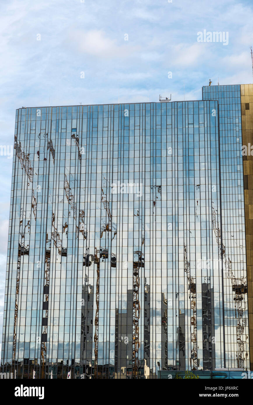 Construction cranes reflected in the glass facade of a skyscraper in Berlin, Germany. Stock Photo