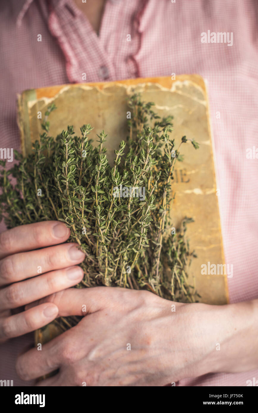 Woman holding old recipe book and herbs Stock Photo
