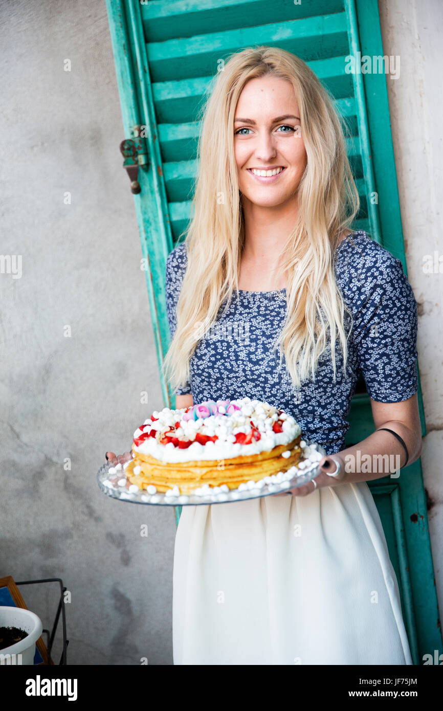 Smiling blonde woman holding cake Stock Photo