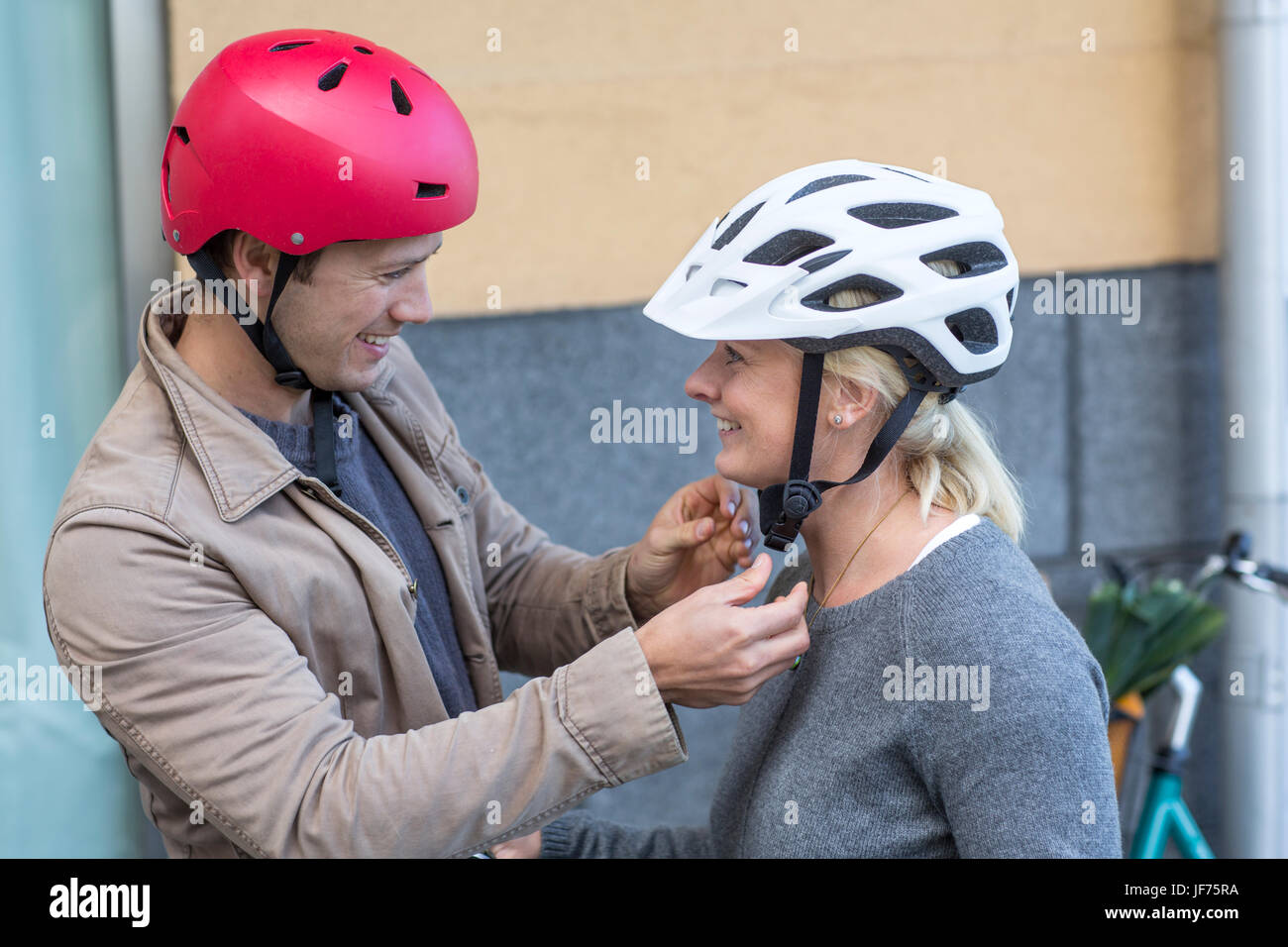 Man helping to his girlfriend to fit cycling helmet Stock Photo Alamy