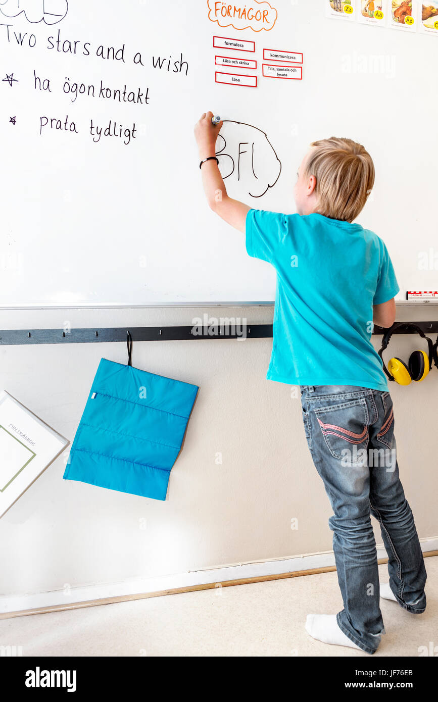 Boy writing on whiteboard Stock Photo