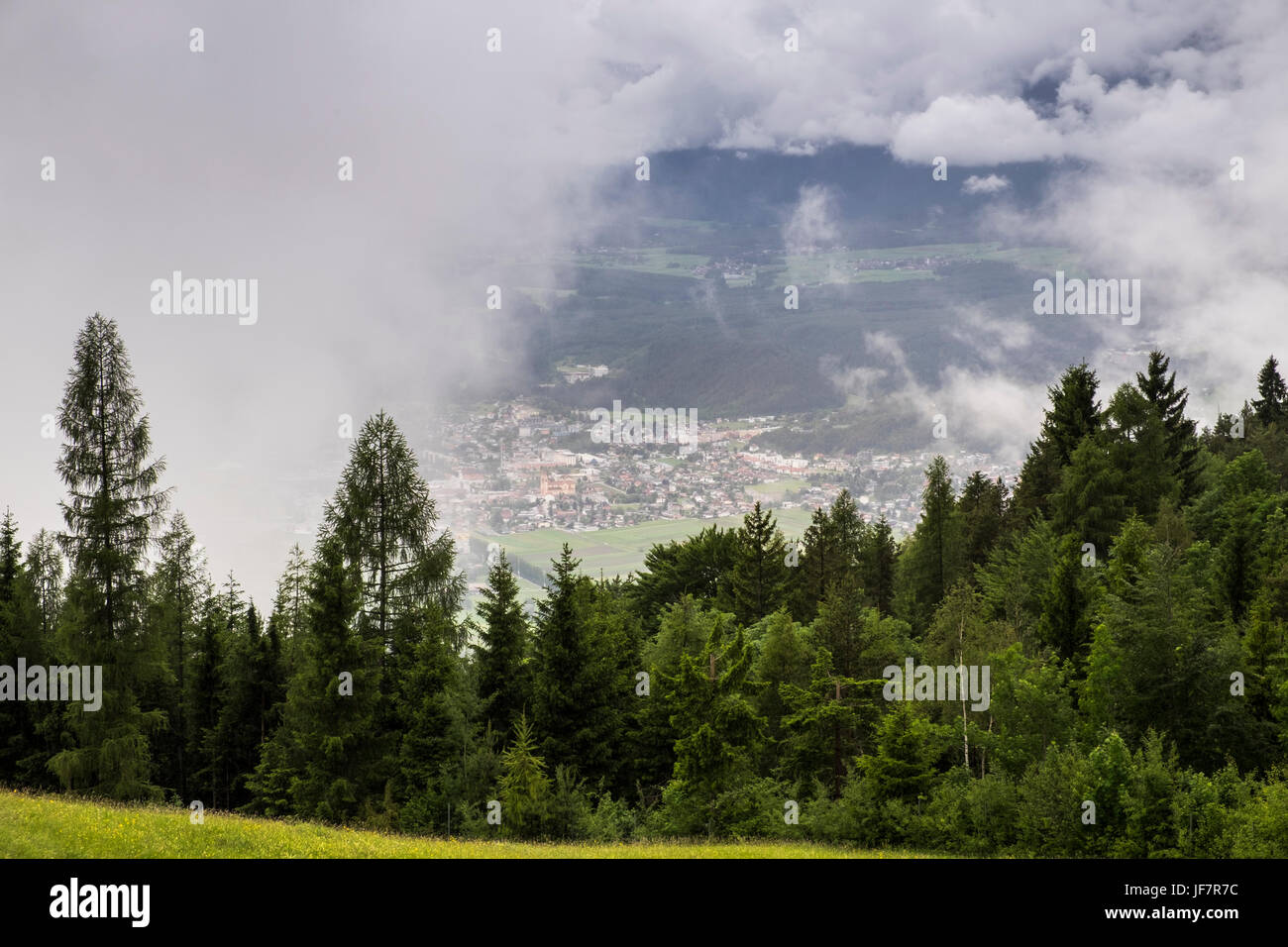 View over fir trees through clearing clouds to the Inn valley and the town of Telfs, Seefeld, Austria Stock Photo