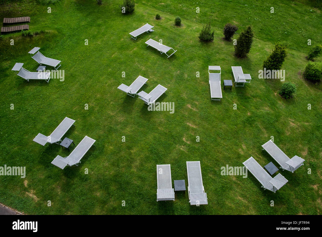 Unoccupied sun loungers on a grass lawn arranged in a circle. Stock Photo