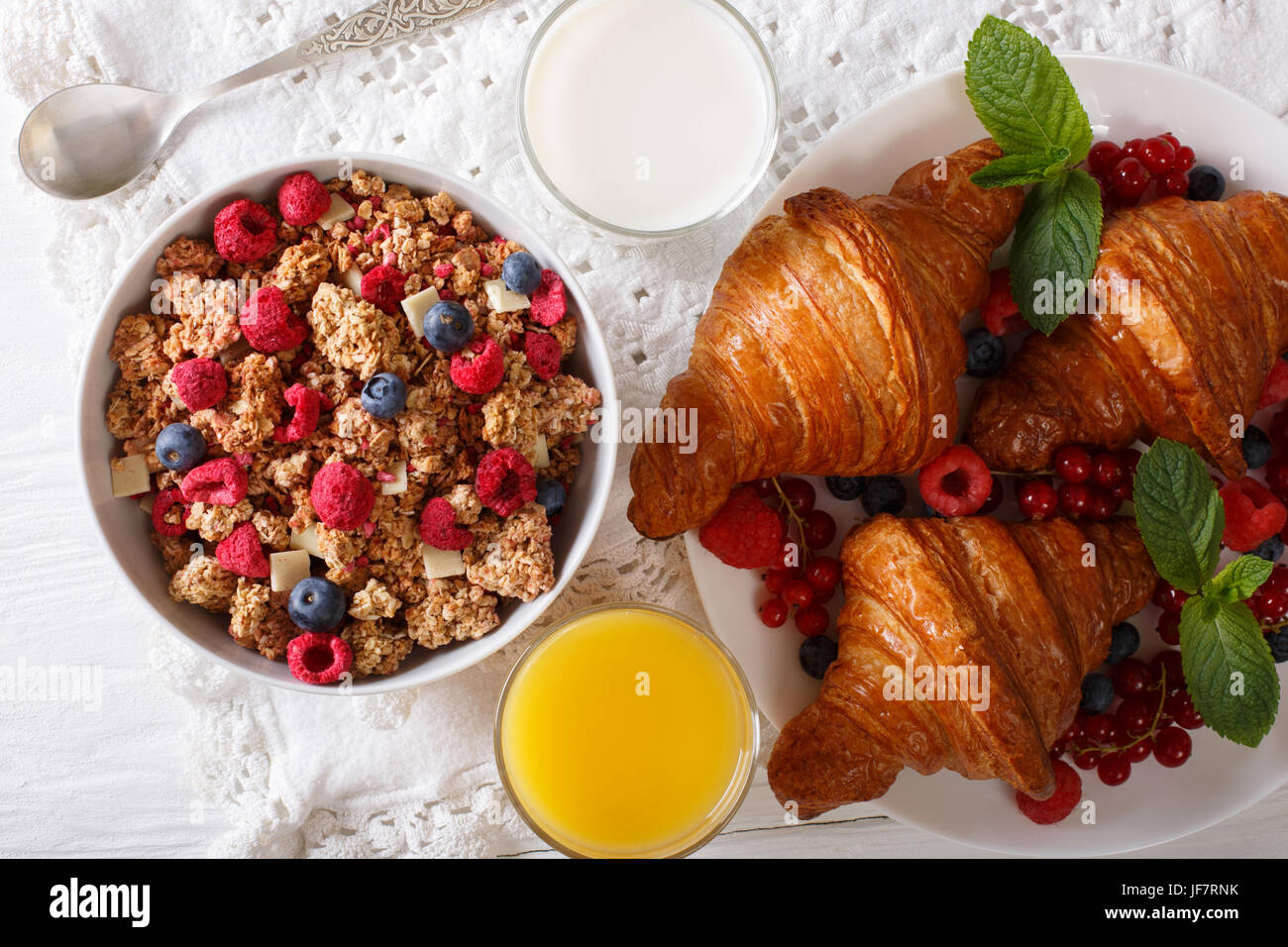 Healthy breakfast: granola with berries and croissants, milk and orange juice close-up on the table. horizontal view from above Stock Photo