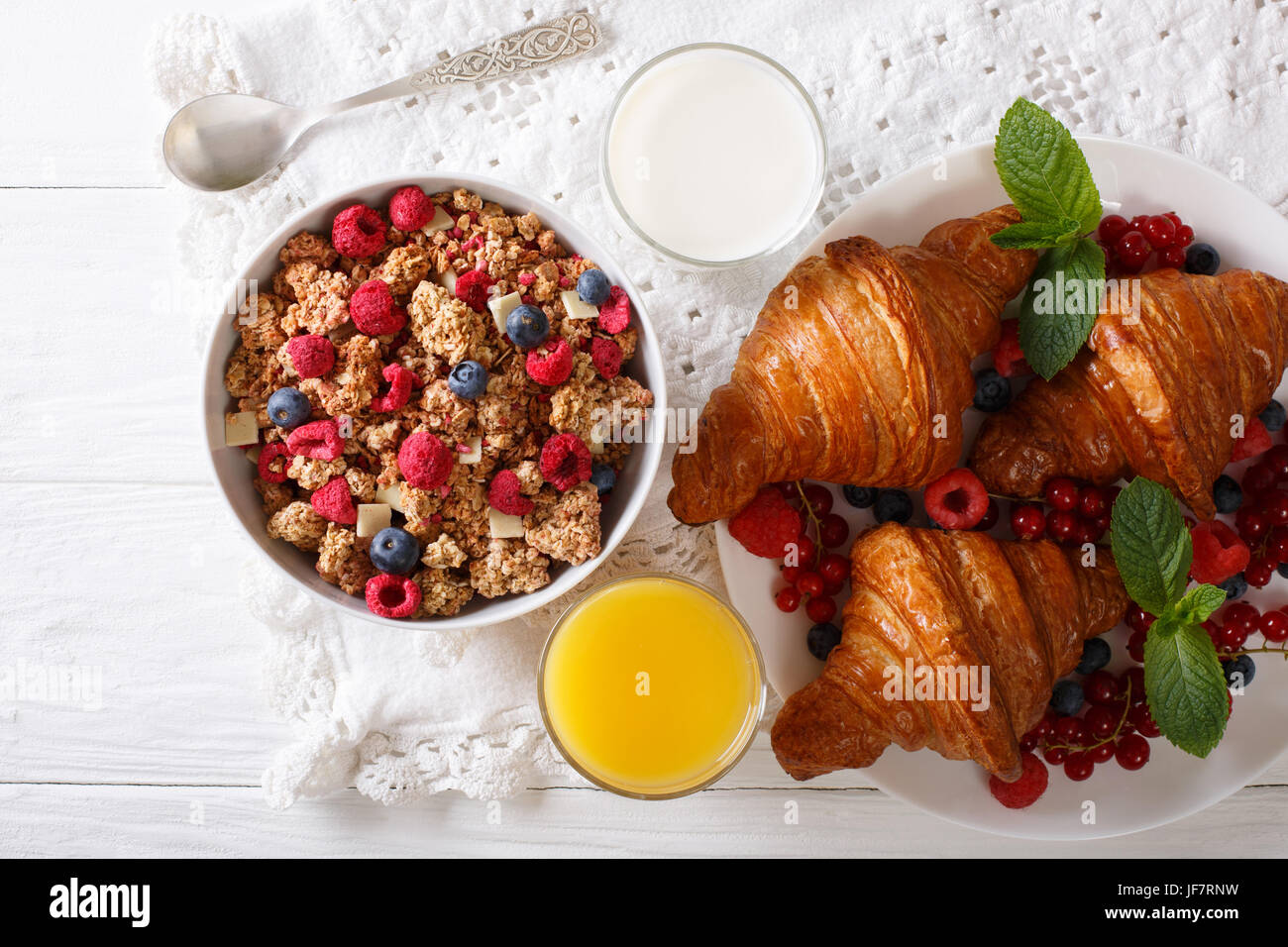 Muesli with berries and croissants, milk and orange juice close-up on the table. horizontal view from above Stock Photo