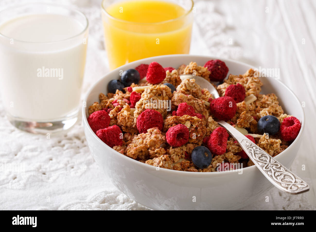 Granola with dried berries, milk and orange juice close-up on a table. horizontal Stock Photo