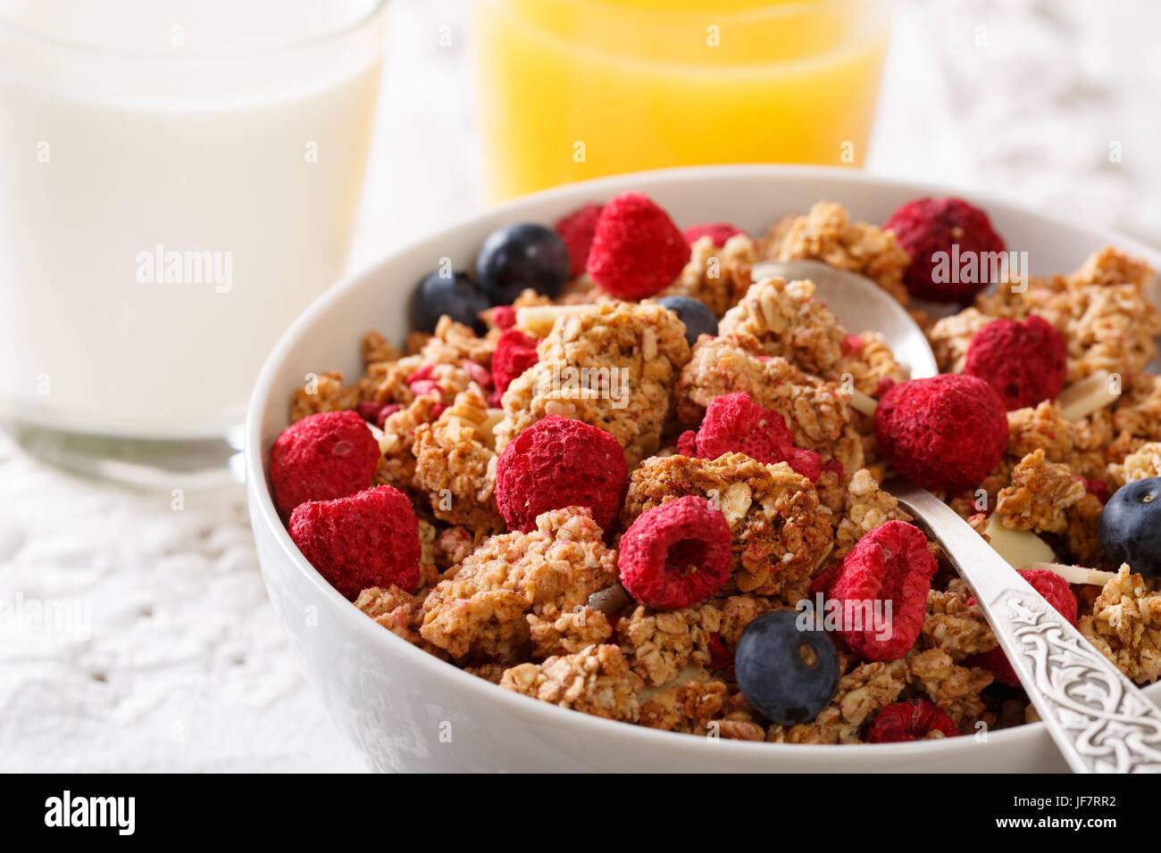 Healthy breakfast: granola with raspberries and blueberries, milk and juice close-up on the table. horizontal Stock Photo