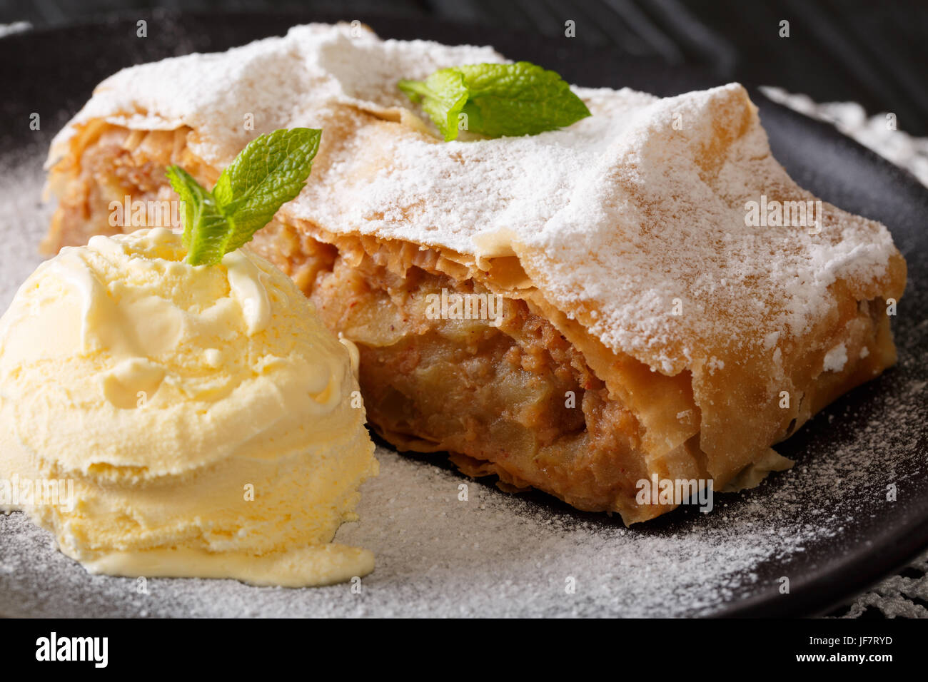 Austrian traditional apple strudel with ice cream and mint closeup on a plate. Horizontal Stock Photo
