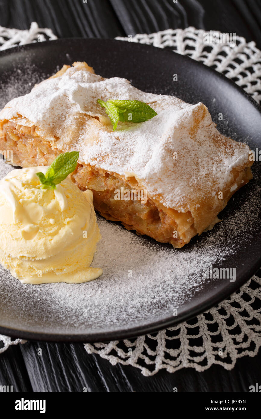 Delicious apple strudel with sugar powder, ice cream and mint closeup on a plate. vertical Stock Photo
