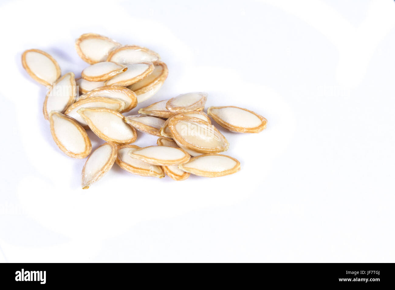 close up of a pile of raw pumpkin seeds isolated on a white background Stock Photo