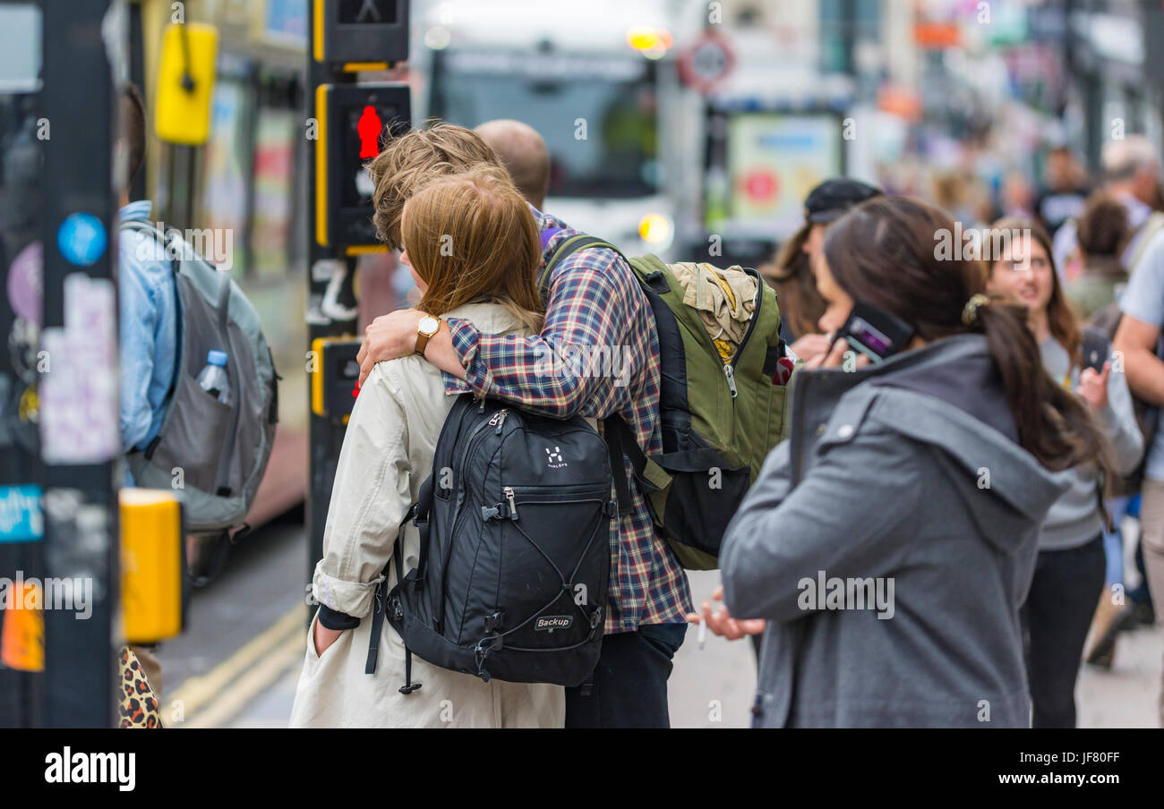 Everyday scene showing young couple with arms around each other in a city full of people in England, UK. Stock Photo