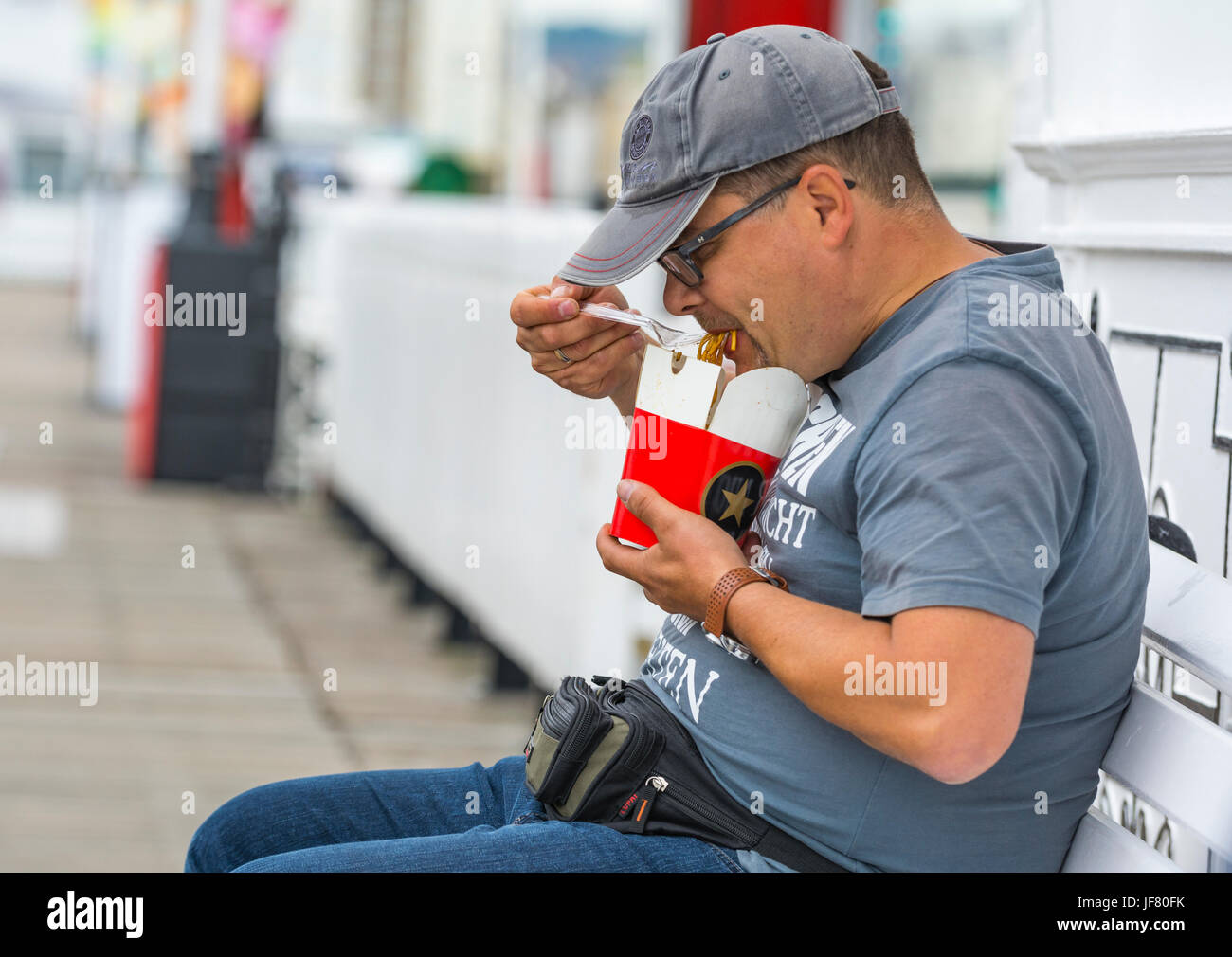 Asian man sitting outside eating noodles. Stock Photo