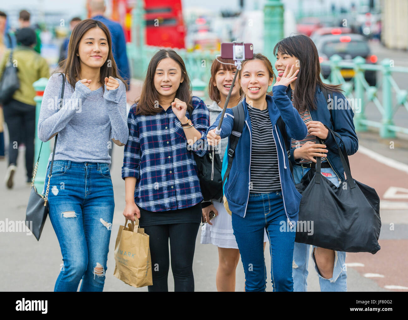 Taking a selfie. Group of Asian friends taking a group selfie using a smartphone on a selfie stick. Stock Photo