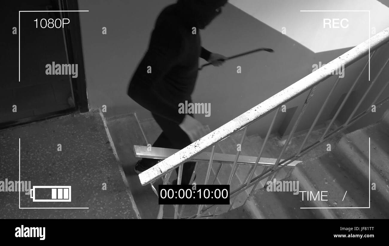 surveillance camera caught the robber in a mask with a crowbar. Stock Photo