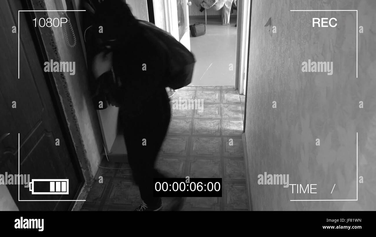 surveillance camera caught the robber in a mask running off with a bag of loot. Stock Photo