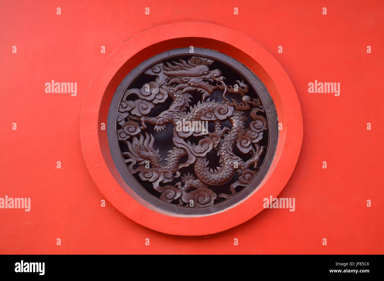 Wooden Carved dragon in circle on red background in Chinese Buddhism Temple in Lumbini, Nepal Stock Photo