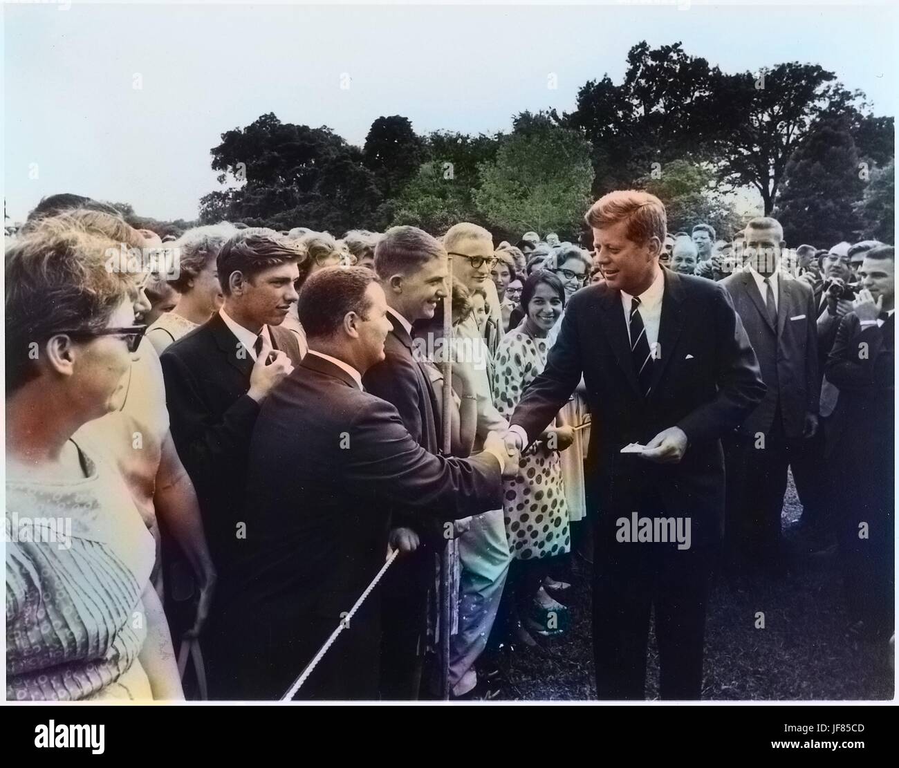 President John F. Kennedy greets volunteers with the Peace Corps on the south lawn at the White House, Washington, D.C, August 9, 1962. Image courtesy National Archives. Note: Image has been digitally colorized using a modern process. Colors may not be period-accurate. Stock Photo
