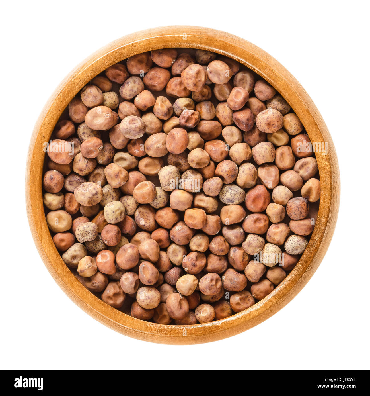 Dried snow pea seeds in wooden bowl. Light brown spherical seeds from the pods of Pisum sativum saccharatum, a legume and variety of pea. Stock Photo