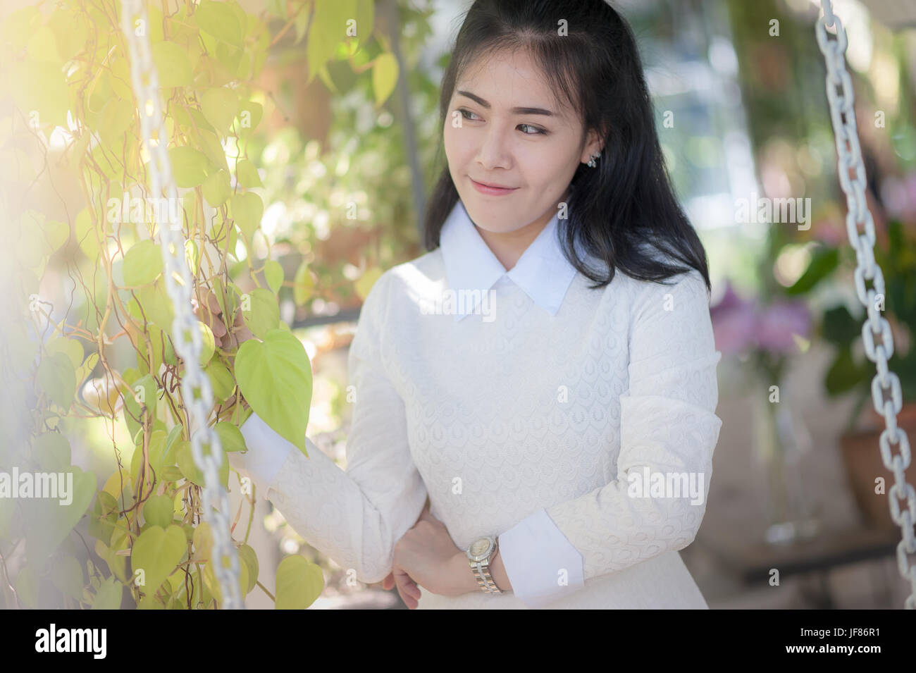 Young attractive Asian woman smiling in green garden. Stock Photo