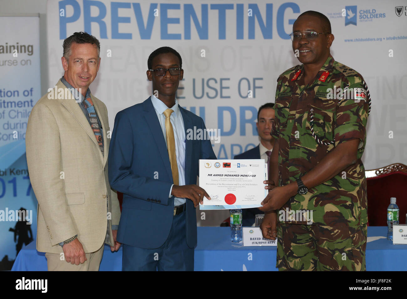 Brigadier Patrick Muta Nderitu (right) the Director of the International Peace and Security Training Centre (IPSTC) and Darin Reeves (left), the Lead Facilitator of the Romeo Dallaire Child Soldiers Initiative, present a certificate to Mr. Ahmed Mohamed Mohamud from Somali Police Force after successful completion of the AMISOM Training of Trainers course on the prevention of the recruitment and use of children as weapons of war, for security sector actors at the International Peace and Security Training Centre, Nairobi, Kenya on May 19, 2017. AMISOM Photo Stock Photo