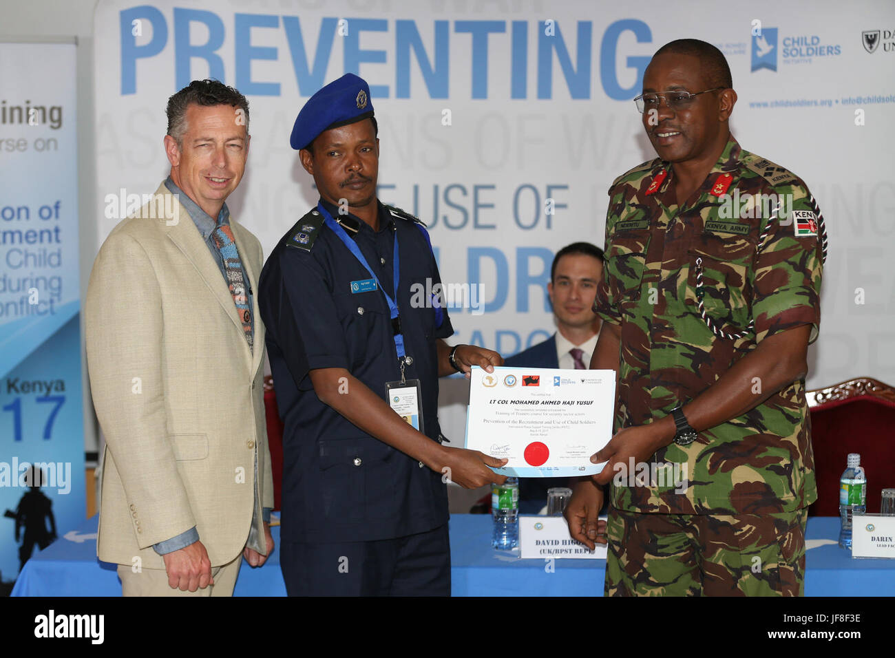 Brigadier Patrick Muta Nderitu (right) the Director of the International Peace and Security Training Centre (IPSTC) and Darin Reeves (left), the Lead Facilitator of the Romeo Dallaire Child Soldiers Initiative, present a certificate to Lt. Col. Mohamed Ahmed Haji Yusuf from Somalia after successful completion of the AMISOM Training of Trainers course on the prevention of the recruitment and use of children as weapons of war, for security sector actors at the International Peace and Security Training Centre, Nairobi, Kenya on May 19, 2017. AMISOM Photo Stock Photo