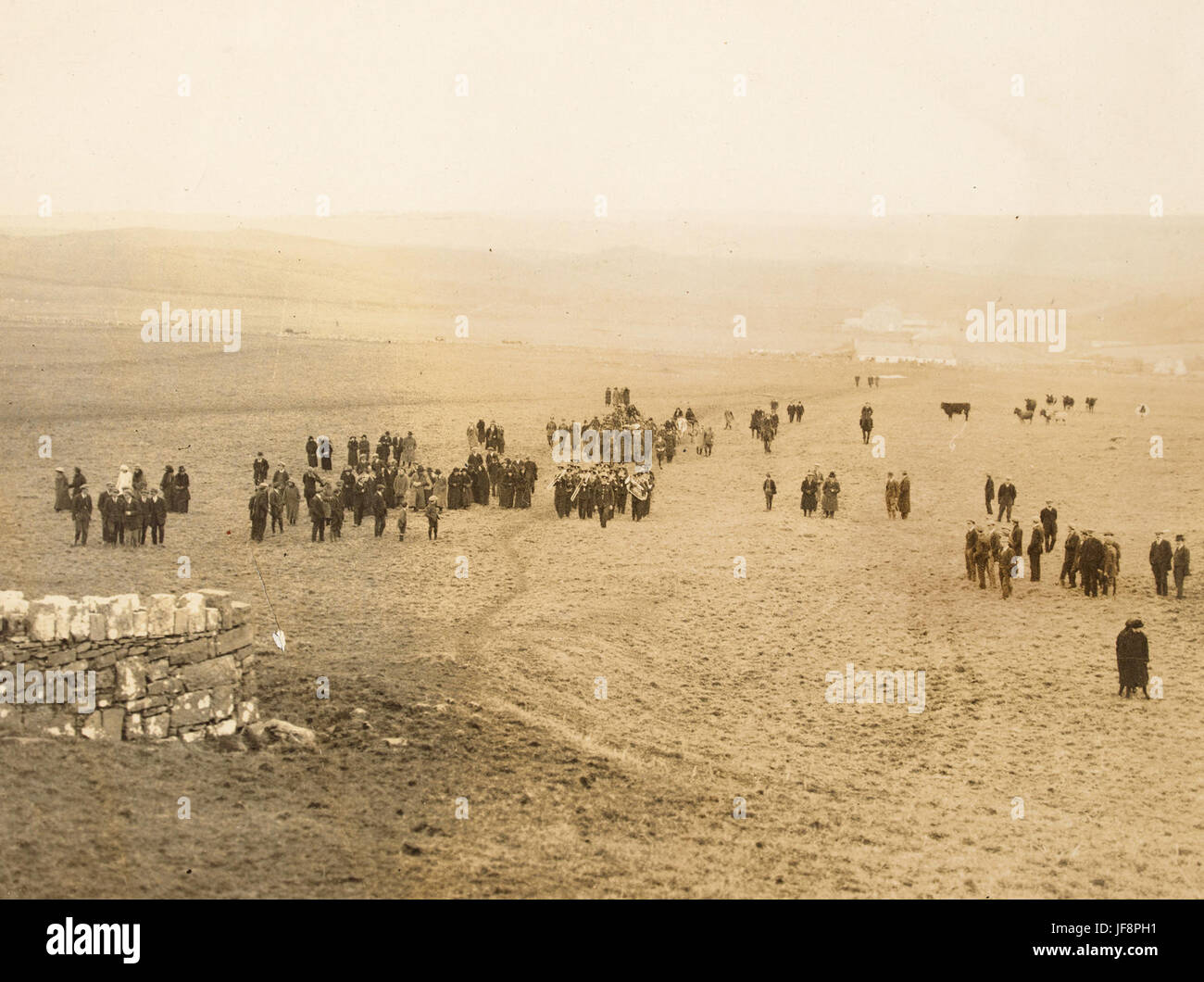 A historic scene from the 1920s showcasing an army band and a crowd gathered in a rural field. This vintage image from the Hogan-Wilson Collection, preserved by the National Library of Ireland, encapsulates a bygone era of military and cultural life. Stock Photo