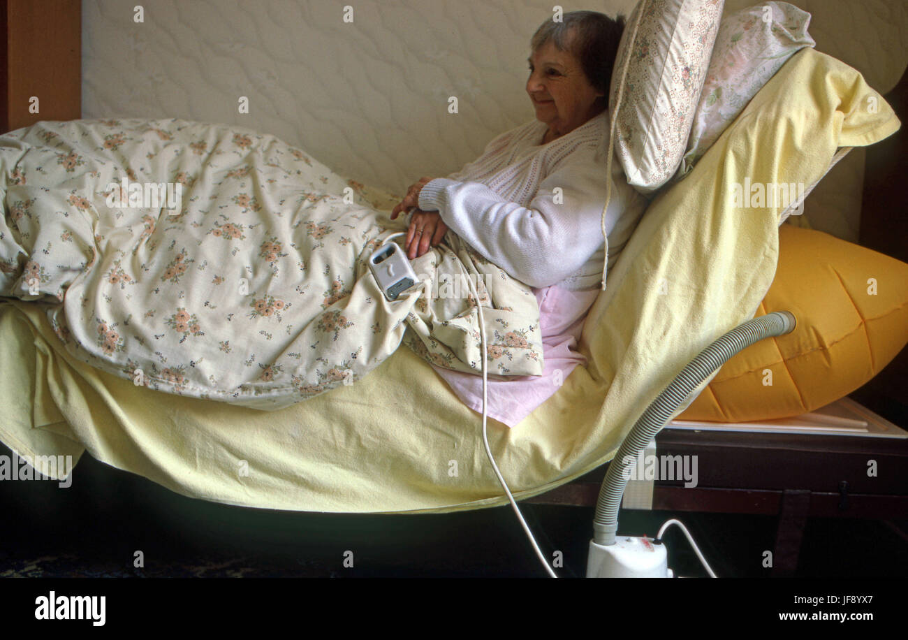 House bound elderly woman in an old style hospital bed with air bag hydraulics Stock Photo