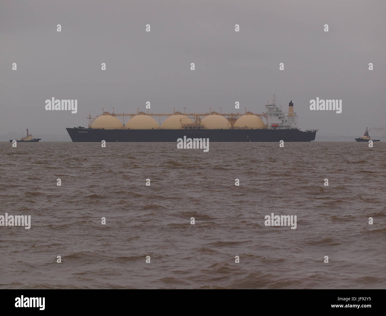 LNG gas ship Gemmata being towed by two tugs. Stock Photo