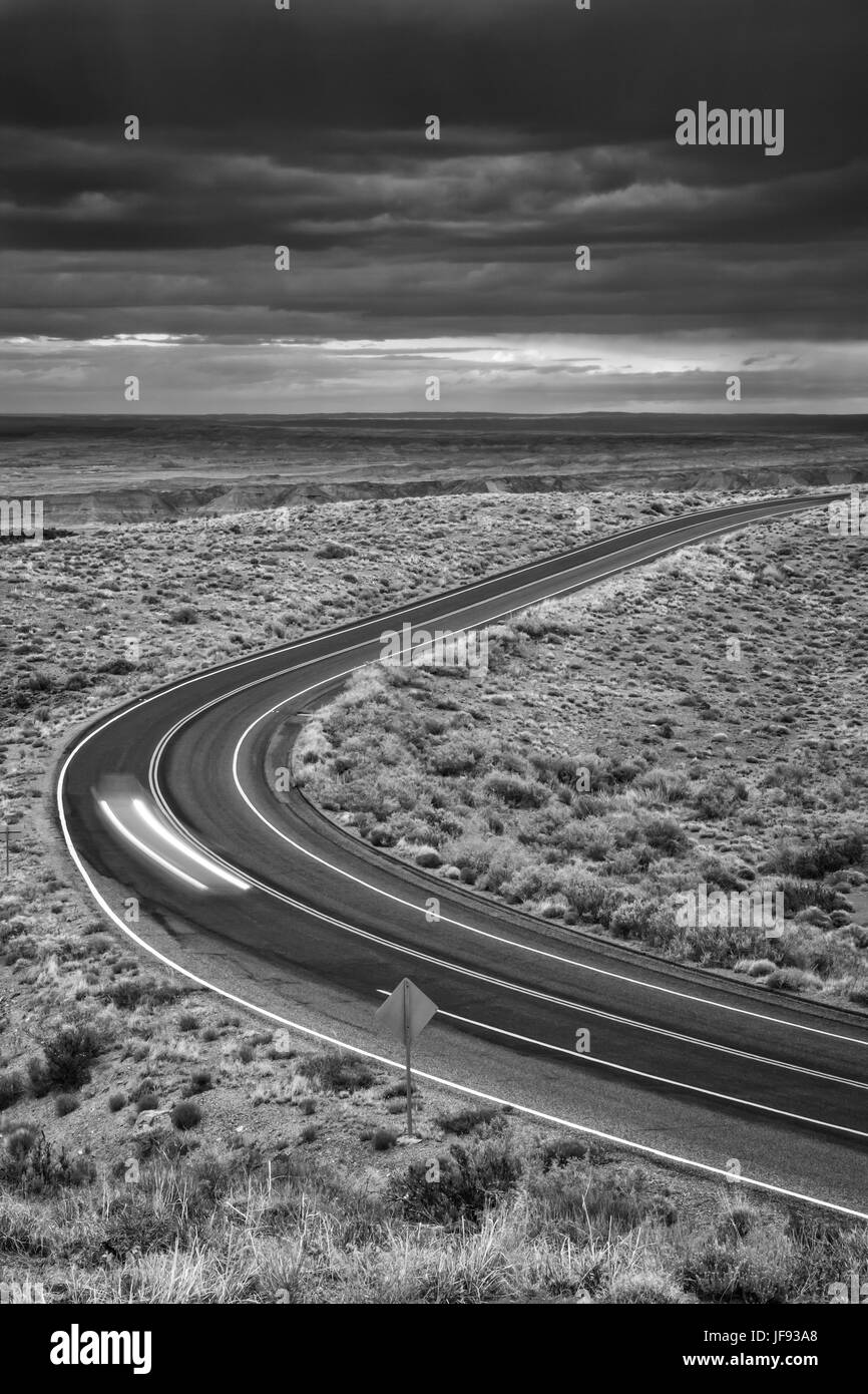A lone car drives across the desert landscape- petrified Forest National Park, Arizona Stock Photo