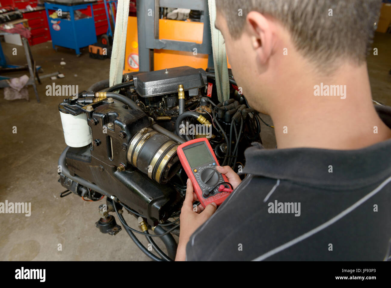 a mechanic man with digital multimeter testing ignition coil Stock