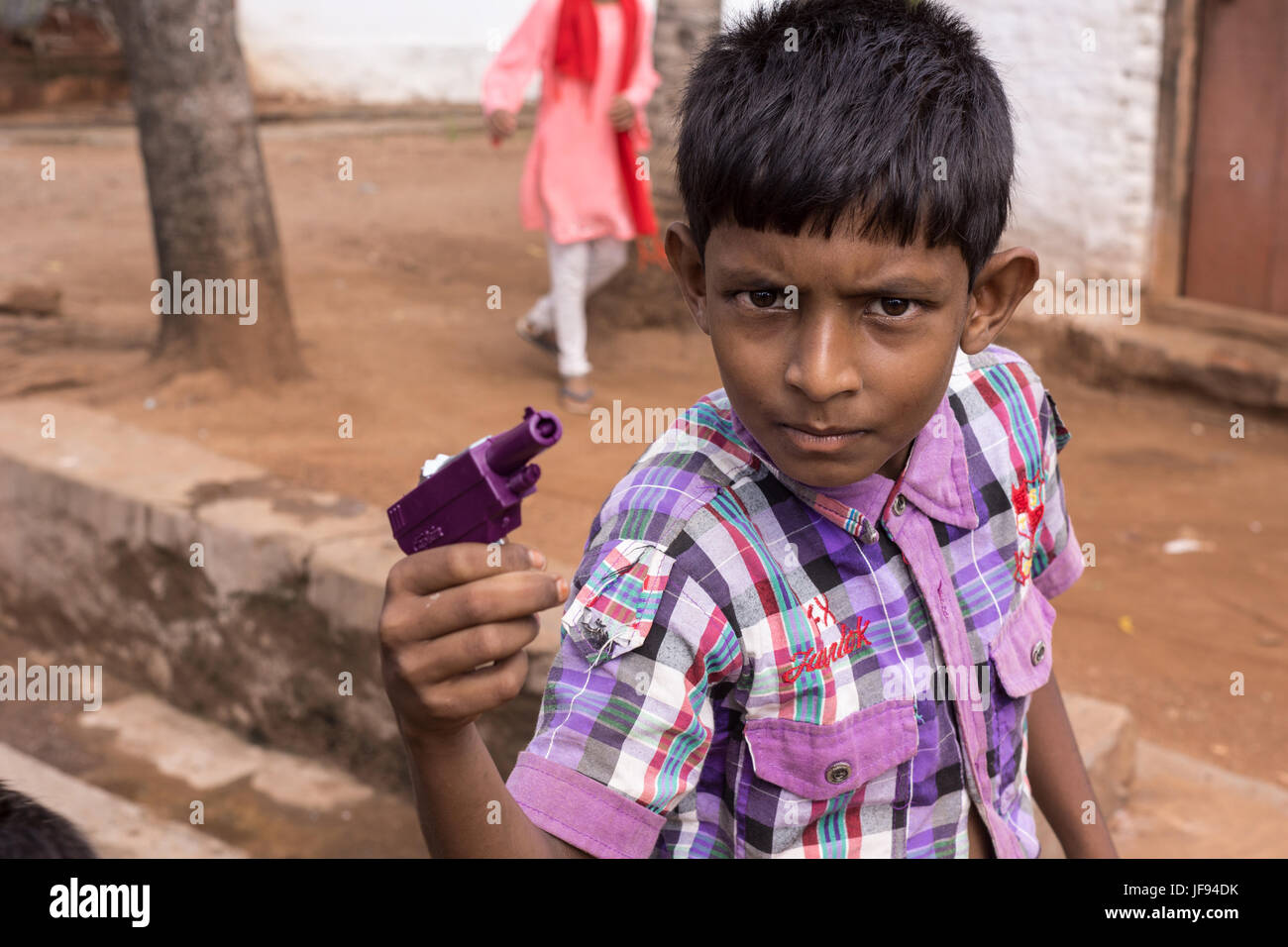 Mysore, India - October 27, 2013: Closeup of preteen boy looks threatening and pretends to kill with his purple toy gun in Mellahalli hamlet. Stock Photo