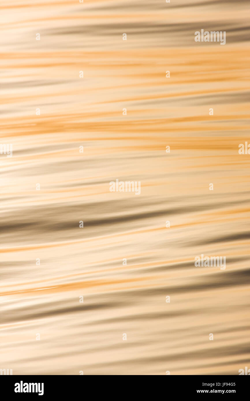 An abstract image of waves, coloured golden by the setting sun. Stock Photo