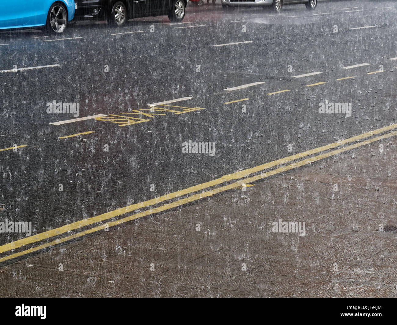 heavy rain torrential on the road affecting traffic on Glasgow street Stock Photo