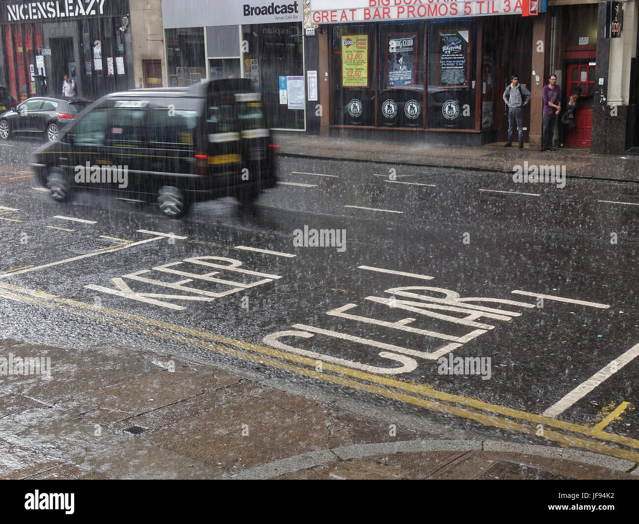 heavy rain torrential on the road affecting traffic on Glasgow street keep clear Nice N Sleazy Stock Photo