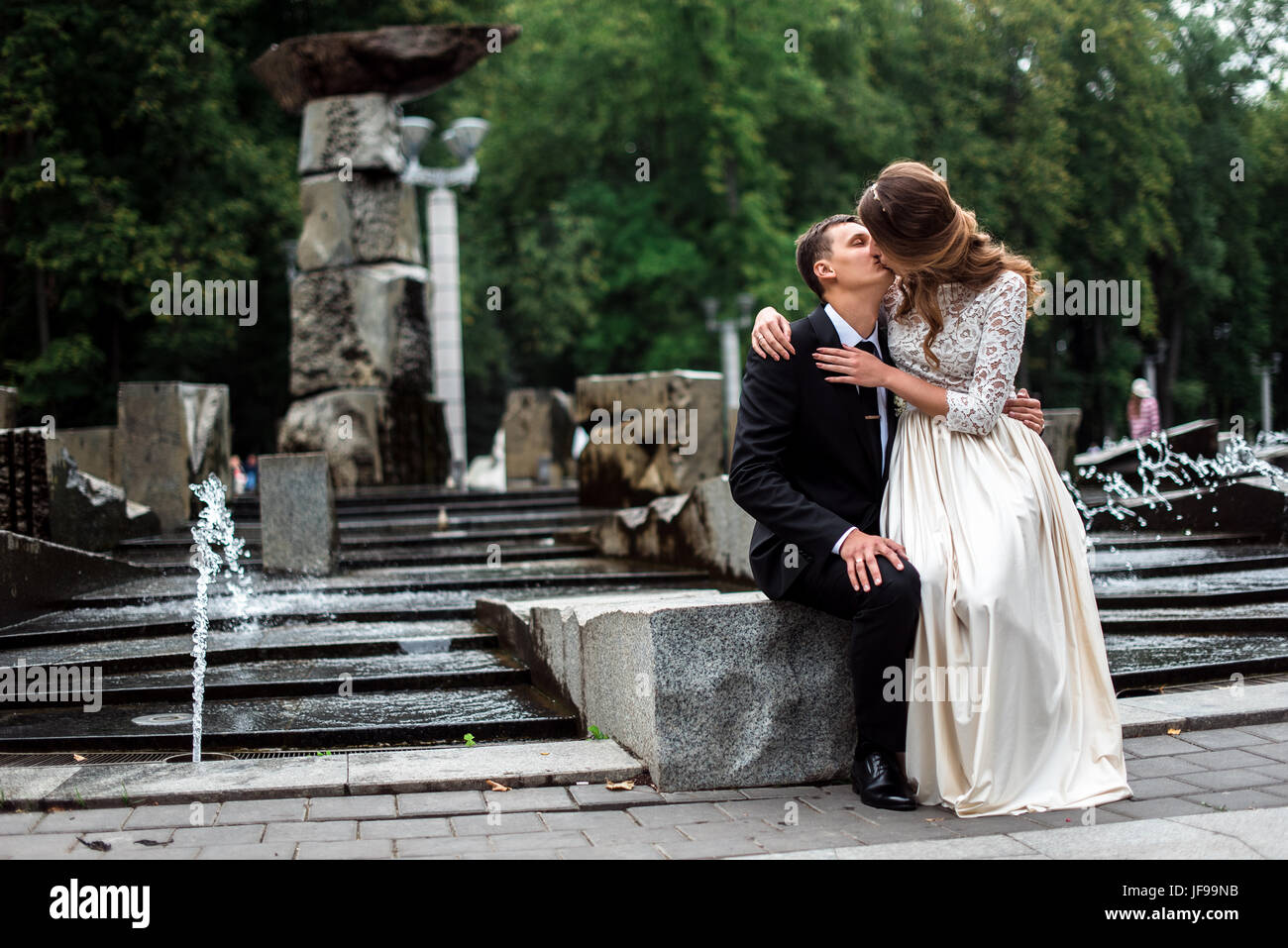 Bride and groom kissing with the fountain on the background Stock Photo ...