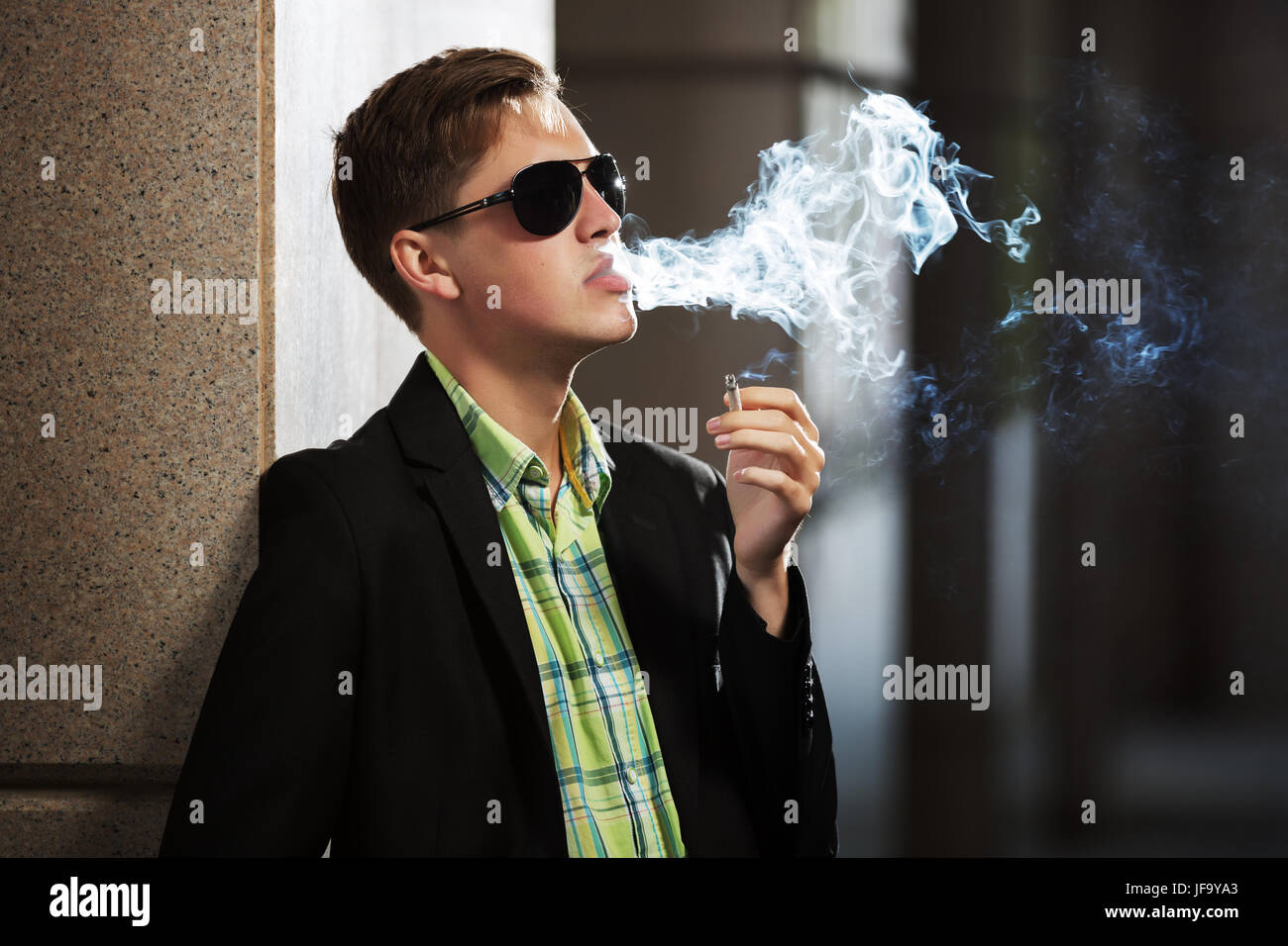 Young fashion man in sunglasses smoking a cigarette Stock Photo