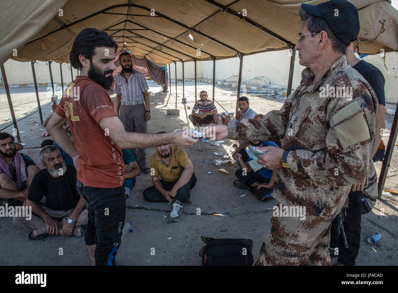 An Iraqi man who fled the heavy fighting between Iraqi forces and the Islamic State in the old city of Mosul receives his identification card after being checked before being transferred to IDP (Internal Displaced People) camps in Iraq, 29 June 2017. According to UNHCR, more than 875,000 people have fled Mosul since the beginning of the fighting in October 2016. Photo: Hugo Passarello Luna/Dpa/dpa Stock Photo